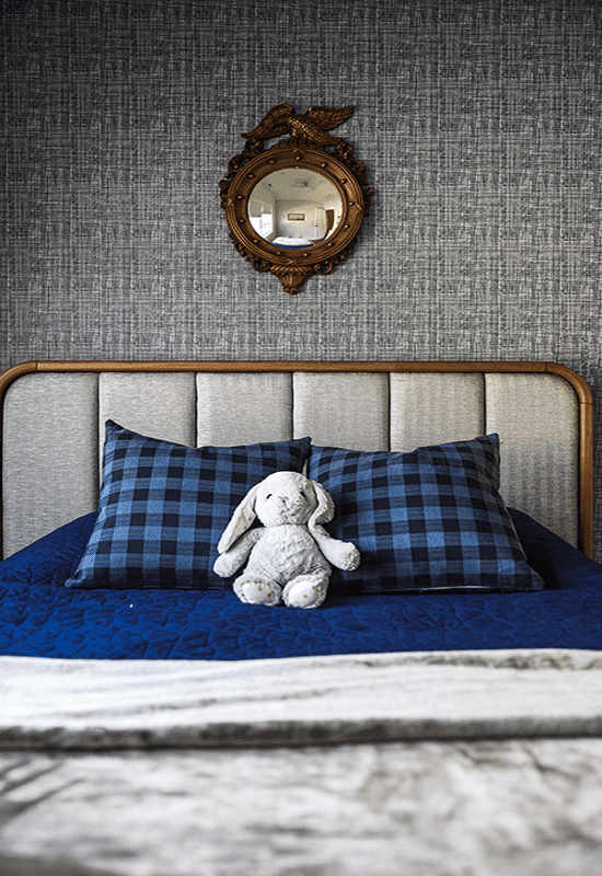 Little boys bedroom design, vintage mirror, custom wallpaper, and checkered pillows