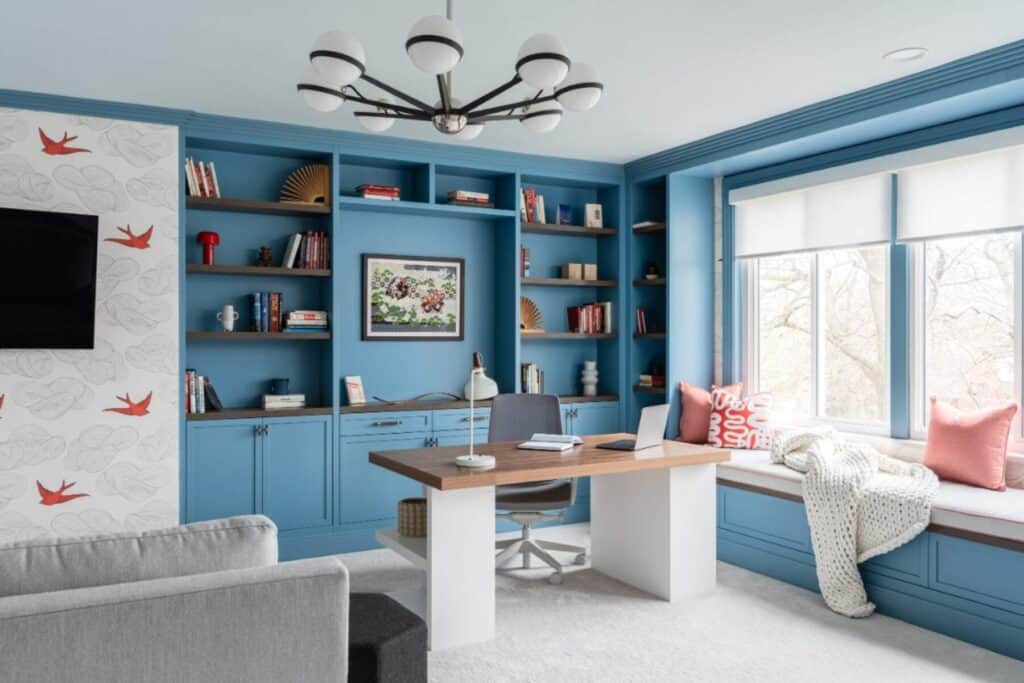 Custom blue built-ins with walnut desk and whimsical wallpaper.