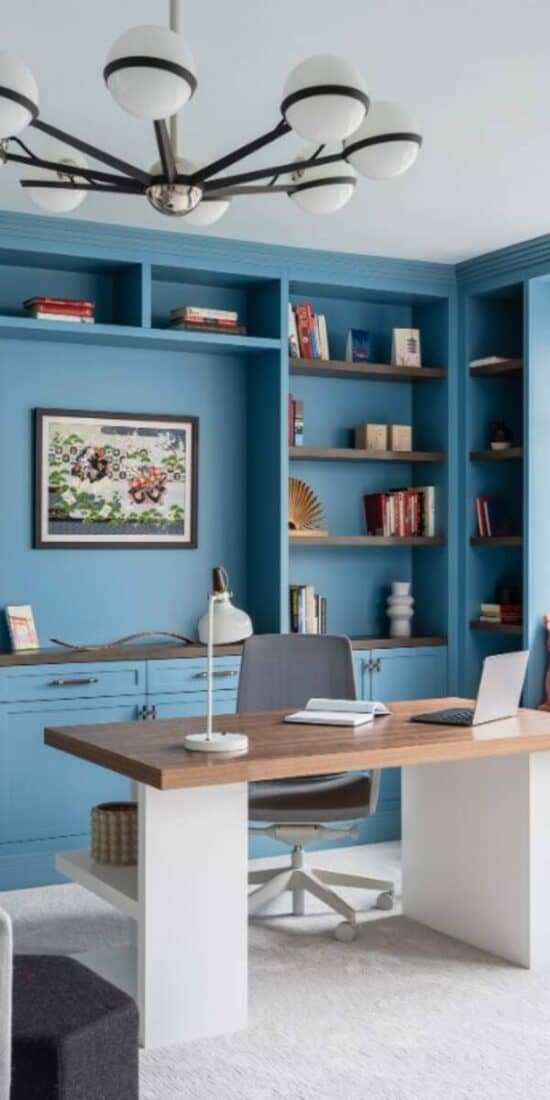 Custom blue built-ins with walnut desk and whimsical wallpaper.